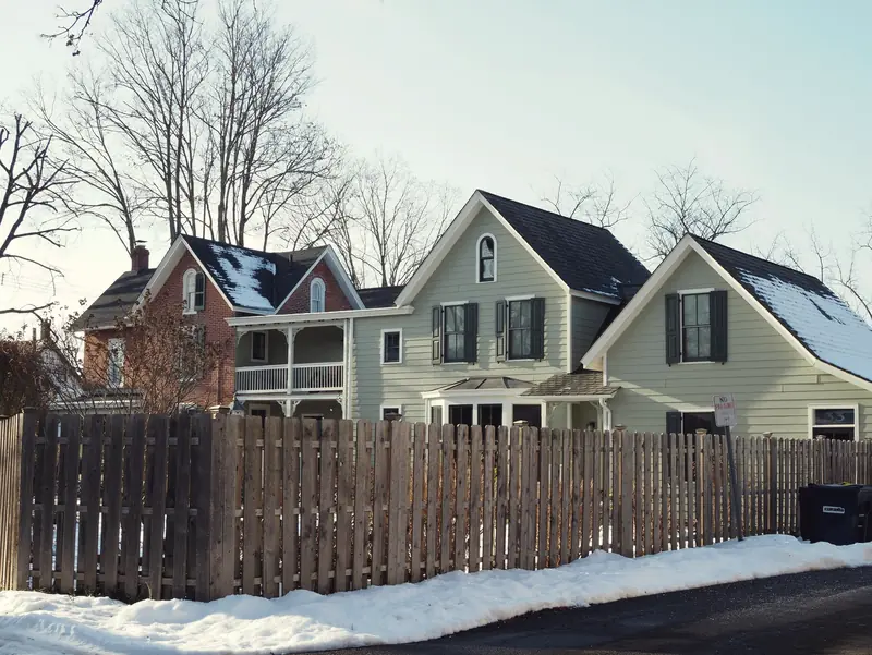 Historic homes behind a wooden fence after a snowfall